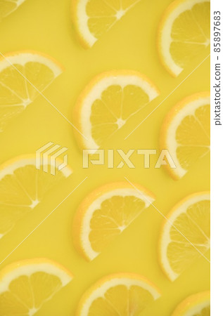 Half slices of lemon lined up on one side, vertical composition inverted Half slices of lemon lined up on one side, vertical composition inverted 85897683