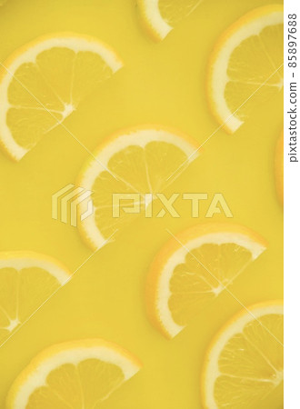 Half slices of lemon lined up on one side, vertical composition inverted Half slices of lemon lined up on one side, vertical composition inverted 85897688