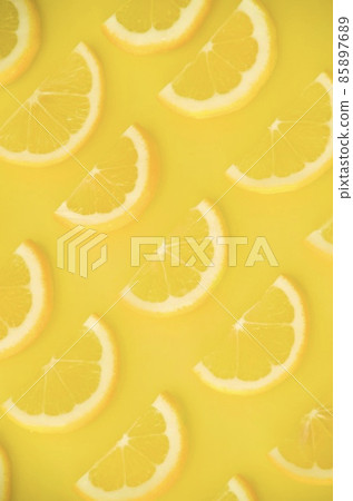 Half slices of lemon lined up on one side, vertical composition inverted Half slices of lemon lined up on one side, vertical composition inverted 85897689