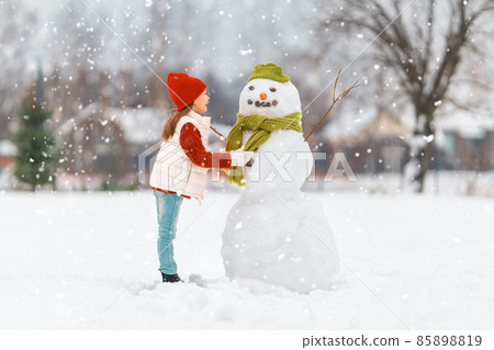 girl playing with a snowman girl playing with a snowman 85898819