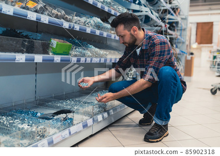 a customer in a hardware store chooses self-tapping screws, screws and nuts a customer in a hardware store chooses self-tapping screws, screws and nuts 85902318