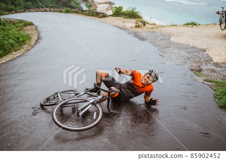 Exhausted cyclist fell down on the road 85902452