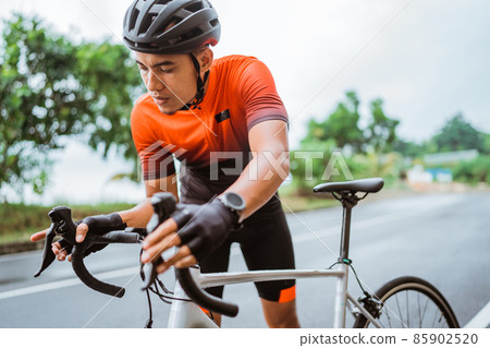 asian road biker checking his brake condition asian road biker checking his brake condition 85902520