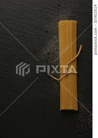 pasta concept a bundle of long slim pasta being placed on the black background 85902814