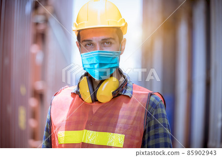 Portrait man dock worker under inspection and checking production process on dock station with radio communication by wearing safety mask to protect for pollution and virus in factory. Portrait man dock worker under inspection and checking production process on dock station with radio communication by wearing safety mask to protect for pollution and virus in factory. 85902943