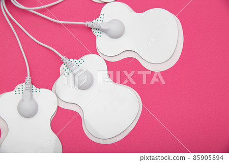 Electrical electrodes for stimulating the patient's body on a pink background. Acupuncture massager 85905894