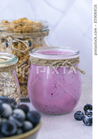 Blueberry smoothie topped with blueberries. A glass of breakfast protein smoothie drink made from pureed raw blueberries, banana, milk, yogurt, and cottage cheese. 85906916