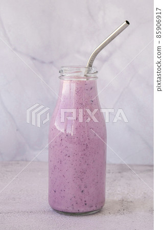 Blueberry smoothie topped with blueberries. A glass of breakfast protein smoothie drink made from pureed raw blueberries, banana, milk, yogurt, and cottage cheese. 85906917