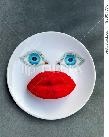 A plate with a face print, blue eyes and a cake in the form of red lips A plate with a face print, blue eyes and a cake in the form of red lips 85907776