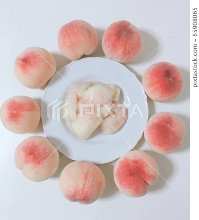 Lots of freshly picked pink peaches and freshly cut peaches that draw a circle around a white plate Lots of freshly picked pink peaches and freshly cut peaches that draw a circle around a white plate 85908065