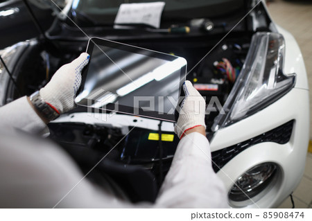 Mechanic use tablet device with black screen in front of car. 85908474