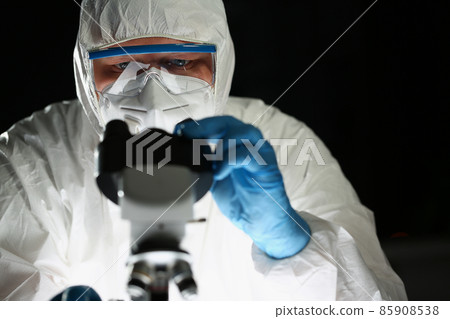 Concentrated person chemist in blue protective gloves look at microscope in chemistry laboratory Concentrated person chemist in blue protective gloves look at microscope in chemistry laboratory 85908538