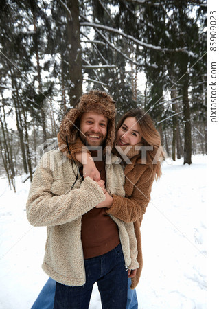 People, season, love and leisure concept - happy couple hugging and laughing outdoors in winter. Couple embracing and having fun in snowy winter park People, season, love and leisure concept - happy couple hugging and laughing outdoors in winter. Couple embracing and having fun in snowy winter park 85909023
