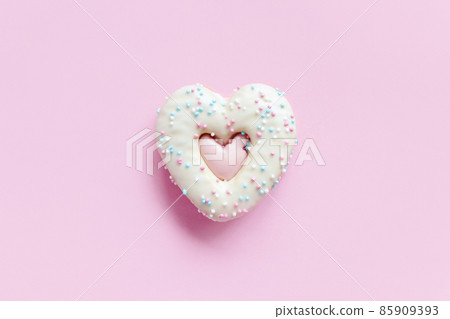 Flat lay of heart shaped gingerbread cookie with sprinkles and icing on pink background Flat lay of heart shaped gingerbread cookie with sprinkles and icing on pink background 85909393