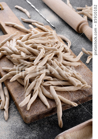 Whole grain wheat apulian pasta called Pizzarieddi o maccaruni on black table. Italian homemade pasta background closeup 85910102