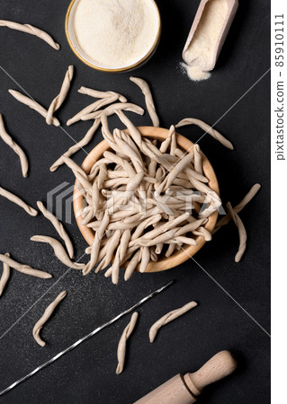 Whole grain wheat apulian pasta called Pizzarieddi or maccaruni on black table. Italian homemade pasta background, above 85910111