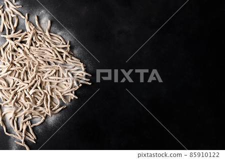 Whole grain wheat apulian pasta called Pizzarieddi or maccaruni on black table. Italian homemade pasta background, above 85910122