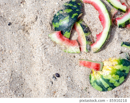 Flat lay. Eaten watermelon and melon rinds on the sand on a sunny summer day. The concept of enjoying delicious juicy fruits while relaxing at sea. Copy space. 85910218