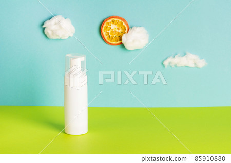 Facial cosmetic product on blue background with cotton wool clouds and orange sun. Eco and natural beauty concept. Art and trend. Front view, copy space 85910880