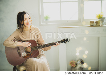 A woman playing the guitar A woman playing the guitar 85911854