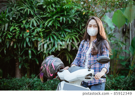Attractive girl standing wearing mask beside motorcycle with copyspace Attractive girl standing wearing mask beside motorcycle with copyspace 85912349