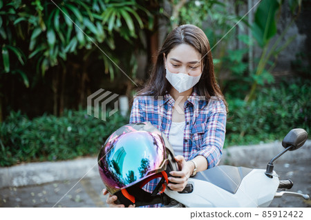 Woman with mask takes helmet before road riding motorbike 85912422