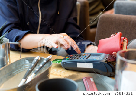 woman pays with a bank credit card for lunch in a restaurant via a wireless terminal. The concept of acquiring services and Internet transfers 85914331