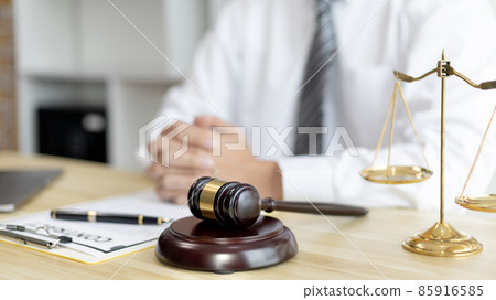 Male lawyer or judge sits and analyzes the case and decides the case with fairness, On the table were the scales of justice and the hammer of honest judgment, Concepts of Law and Legal services. Male lawyer or judge sits and analyzes the case and decides the case with fairness, On the table were the scales of justice and the hammer of honest judgment, Concepts of Law and Legal services. 85916585
