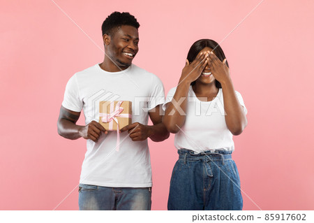 Happy black guy making surprise for his woman holding box Happy black guy making surprise for his woman holding box 85917602