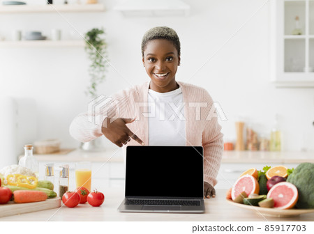 Happy glad excited young black female blogger points finger at pc with empty screen 85917703
