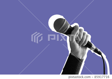 Female hand holding a microphone isolated on lilac Very Peri background Female hand holding a microphone isolated on lilac Very Peri background 85917716
