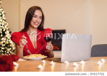 Excited woman having dinner during virtual date on laptop Excited woman having dinner during virtual date on laptop 85917782