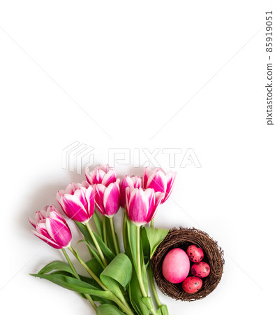 Easter composition with pink eggs in a nest and spring flowers tulips on a white background. Copy space, top view. Easter composition with pink eggs in a nest and spring flowers tulips on a white background. Copy space, top view. 85919051