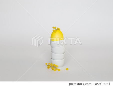 Yellow chicken egg in a stand and yellow flowers on a white background. Easter minimal concept. Copy space. Side view. 85919081