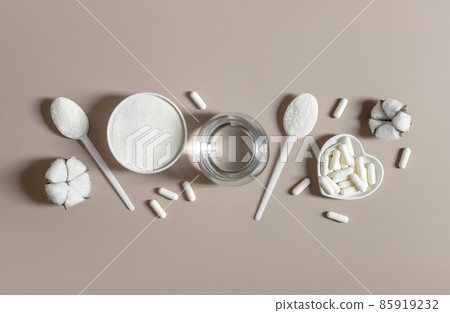 Collagen powder and pills on a beige background. plant or fish based collagen supplement. Healthy lifestyle concept. View from above. Space for text. 85919232