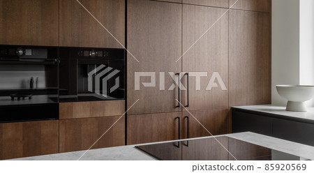 Modern minimalistic kitchen with black and wooden surfaces, marble kitchen island top and household appliances. Modern Concept For Interior Design And Architecture. 85920569