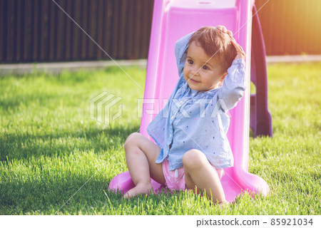 Little and cute girl play on slide and make a grimace while she play. 85921034