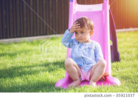Little and cute girl play on slide and make a grimace while she play. 85921037