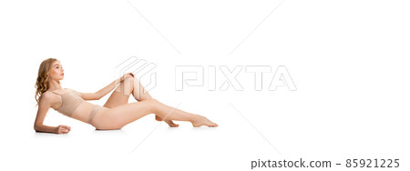One young pretty girl, blonde in underwear sitting on floor isolated over white studio background. Natural beauty concept. One young pretty girl, blonde in underwear sitting on floor isolated over white studio background. Natural beauty concept. 85921225