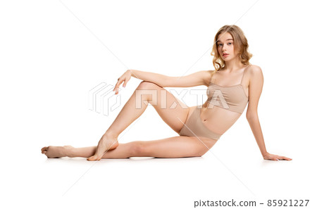 One young pretty girl, blonde in underwear sitting on floor isolated over white studio background. Natural beauty concept. One young pretty girl, blonde in underwear sitting on floor isolated over white studio background. Natural beauty concept. 85921227
