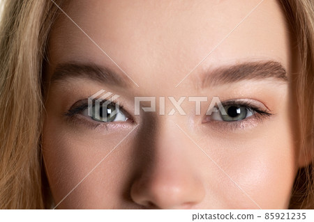 Cropped close-up face of young beautiful well-kept skinned girl without makeup. Facial expression, cosmetics, natural beauty concept. Cropped close-up face of young beautiful well-kept skinned girl without makeup. Facial expression, cosmetics, natural beauty concept. 85921235