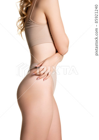 Beautiful body of young slim woman in nude color underwear isolated on light studio background. Natural beauty concept. Beautiful body of young slim woman in nude color underwear isolated on light studio background. Natural beauty concept. 85921240