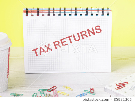 tax returns text on a notebook standing on a table on a yellow background tax returns text on a notebook standing on a table on a yellow background 85921305