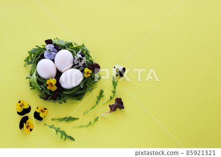 Egg nest made from salad leaves and flowers with white eggs in it. Easter decor. Egg nest made from salad leaves and flowers with white eggs in it. Easter decor. 85921321