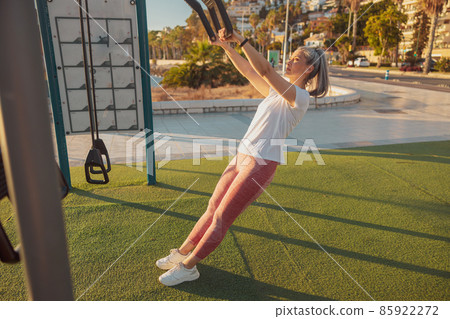 Full-length photo of mature lady in sports clothing exercising at outdoor sports ground Full-length photo of mature lady in sports clothing exercising at outdoor sports ground 85922272