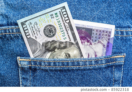 American dollar and UK pounds banknotes stick out of the jeans pocket 85922318