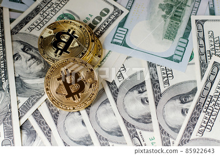 Physical Gold Bitcoin Coin against dollar bills and smartphone on a purple background. Physical Gold Bitcoin Coin against dollar bills and smartphone on a purple background. 85922643