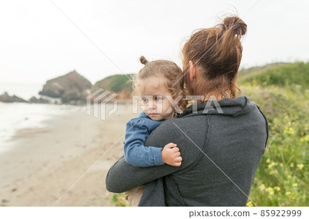 Mother and little daughter standing rock ocean beach autumn season Mother and little daughter standing rock ocean beach autumn season 85922999