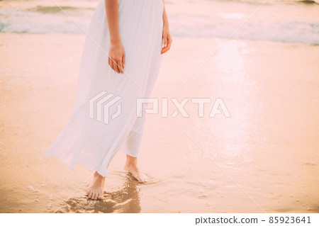 Goa, India. Close Legs And Hands Of Young Woman In White Dress Near Sea Ocean In Sunny Time Goa, India. Close Legs And Hands Of Young Woman In White Dress Near Sea Ocean In Sunny Time 85923641
