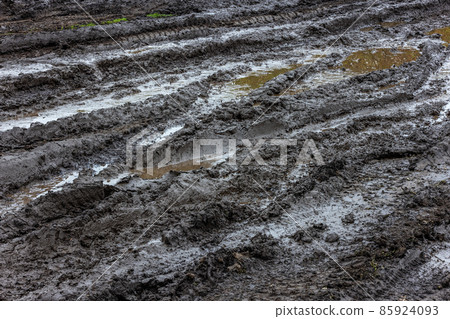 Black wet dirt road with puddles of dirty water at day light Black wet dirt road with puddles of dirty water at day light 85924093